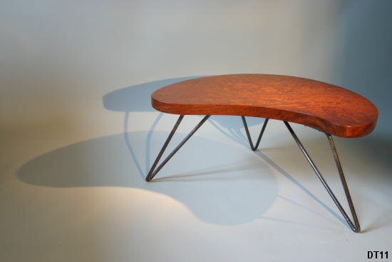 Petite table basse, vers 1950; piètement en fer cintré laqué noir, épais plateau de bois exotique. Dans le goût de Jean Royère.