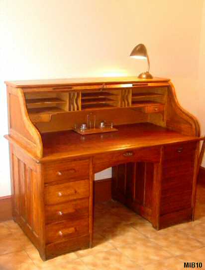 Bureau  cylindre de type dos d'ne vers 1940, rideau coulissant, 5 tiroirs, une porte coulissante, 7 tablettes, intrieur 2 tiroirs, nombreuses tagres. Corps chne massif, coloris noyer dor. Poignes bois.